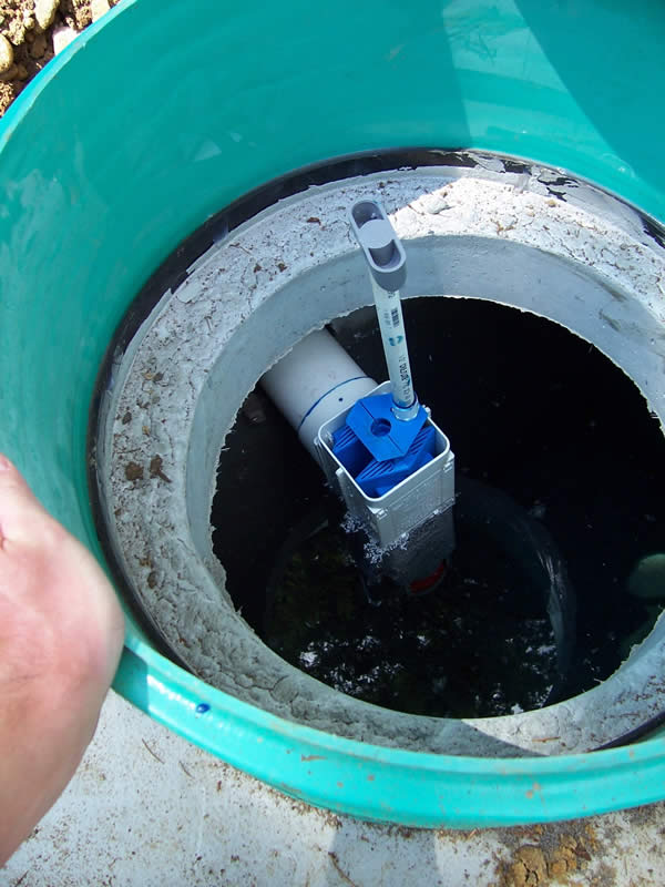 An outlet filter with handle installed in a standard septic tank. The blue filter provides passive filtration and prevents larger pieces of solids and "scum" from entering the downstream components.